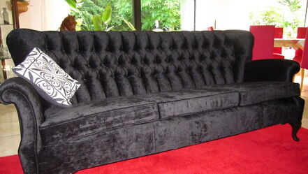 Schwarzes Samtsofa mit Knopfheftung und gemustertem Kissen
